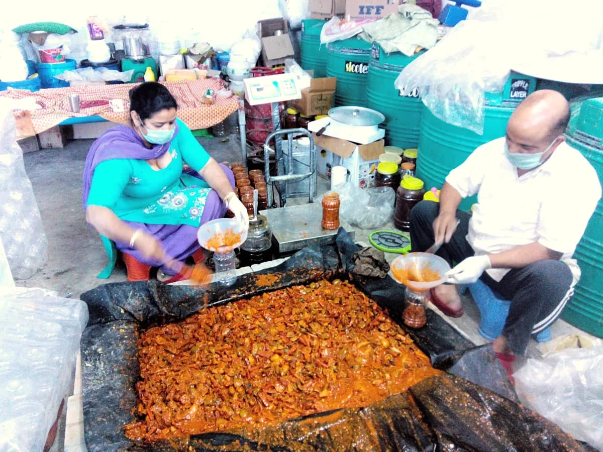 Mixing pickle masala by hand and filling jars